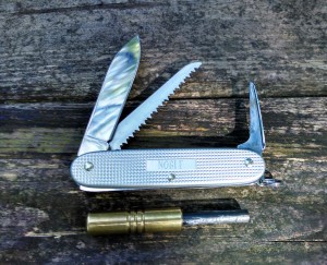 Swiss Army Knife Bushcrafter with Wilderness Solutions Pendant.  With the pendant being small, the combination with SAK awl is excellent.