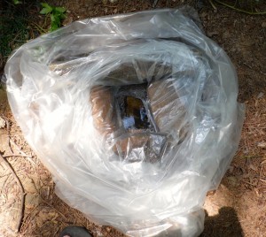 55 Gallon Drum Liner with 36 ounces of water ready to be rock boiled. Sides are supported by rocks and wood. There is a flat rock in the bottom to act as a trivet.